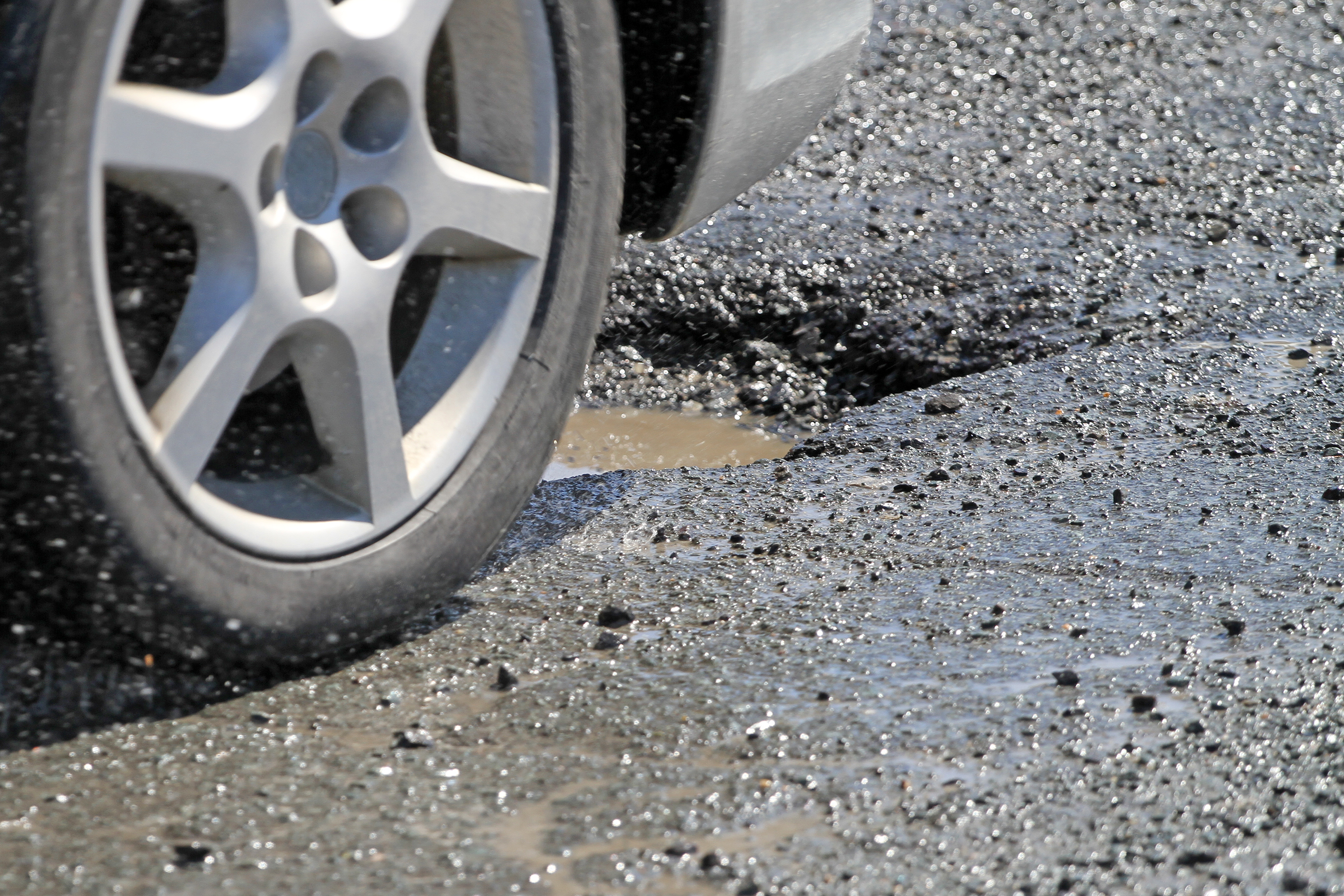 Car Wheel Moments Before Hitting Pothole On City Street